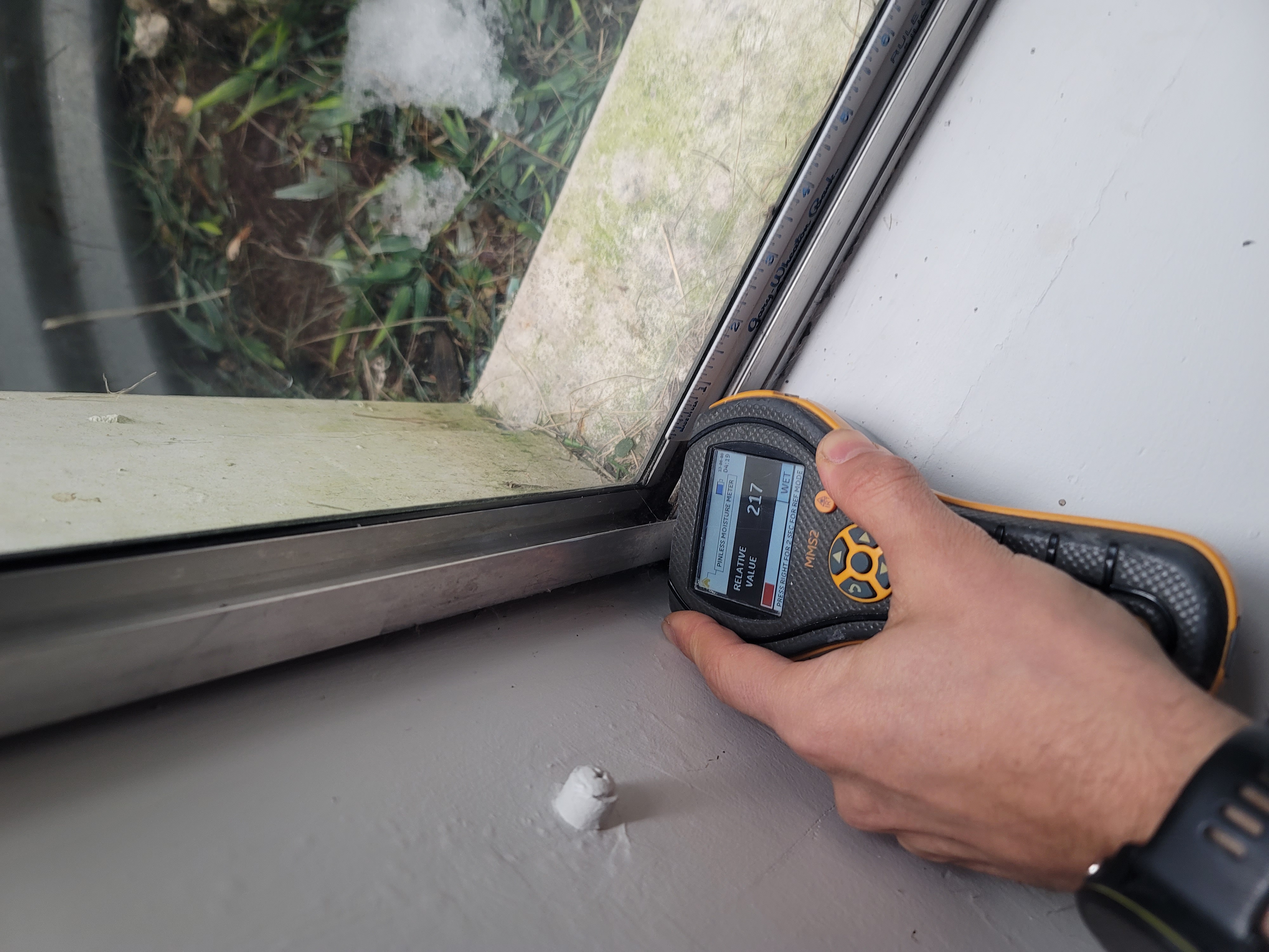 Professional moisture meter measuring humidity levels near window in Miami home